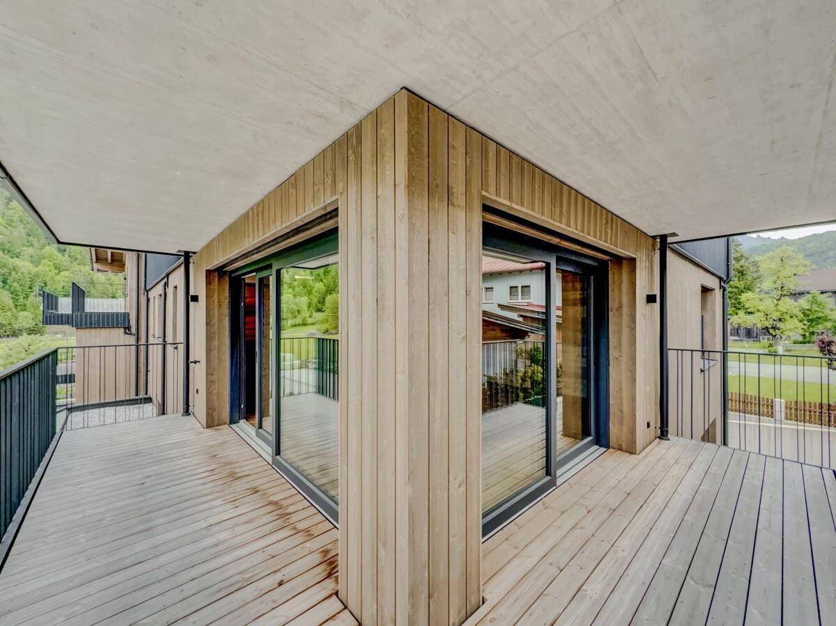 Geräumiger Eckbalkon mit Holzdeck und Metallgeländer, bietet einen schönen Blick ins Grüne.