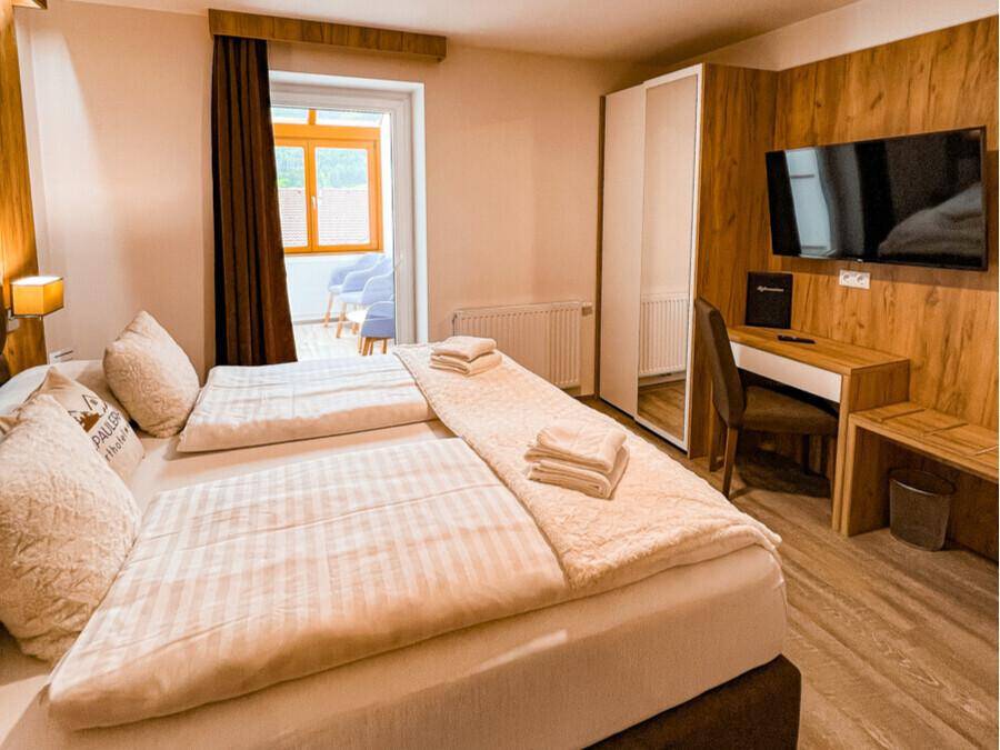 Gemütliches Schlafzimmer mit Doppelbett, Holzakzenten und Zugang zu einem kleinen Balkon.