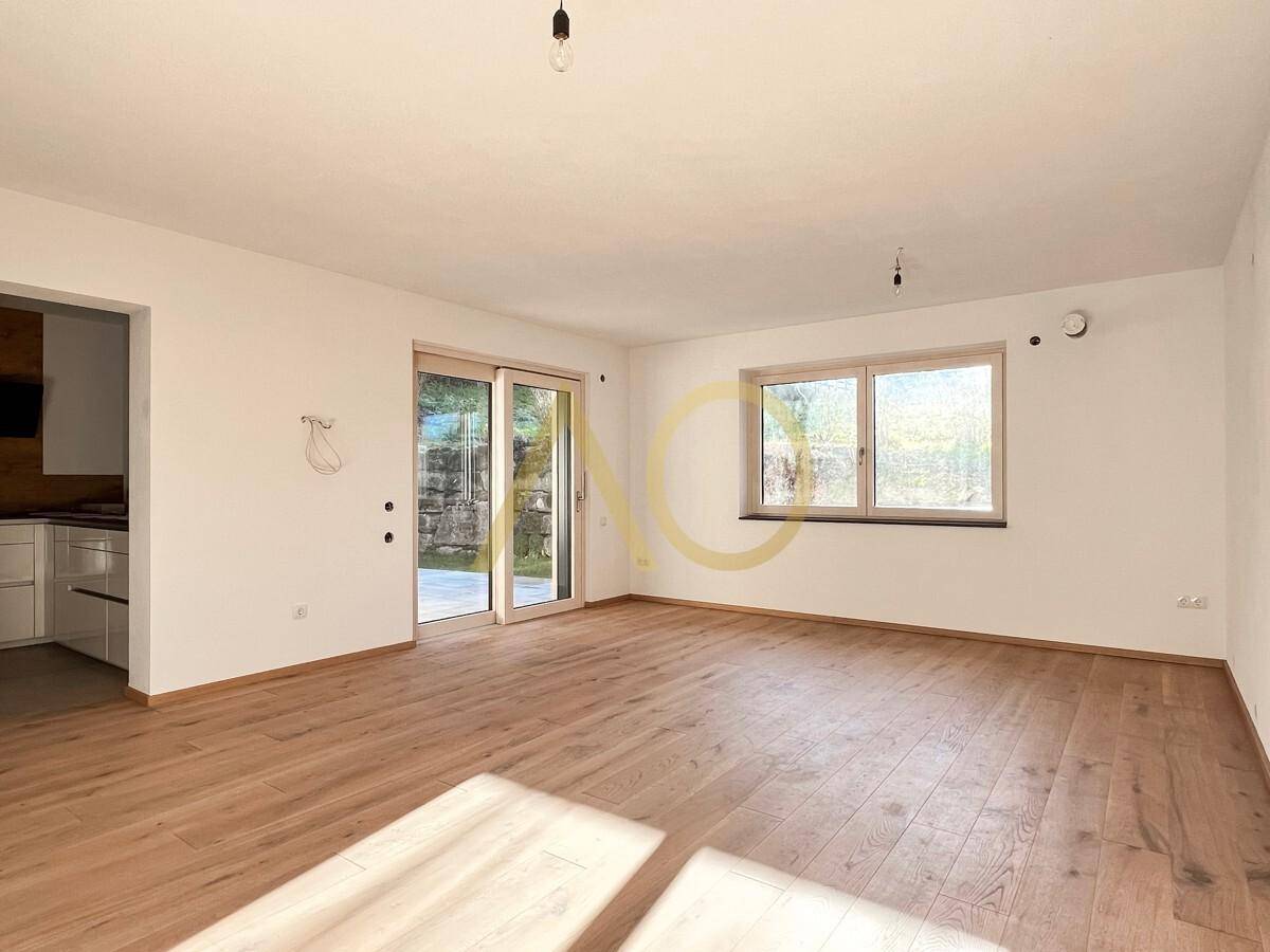 Heller Wohnraum mit Holzboden und großen Schiebetüren zum Außenbereich.