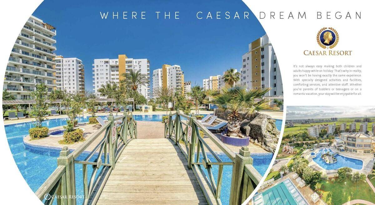 Weitläufige Poollandschaft des Resorts mit einer Holzbrücke, umgeben von modernen Apartmentgebäuden und Palmen.