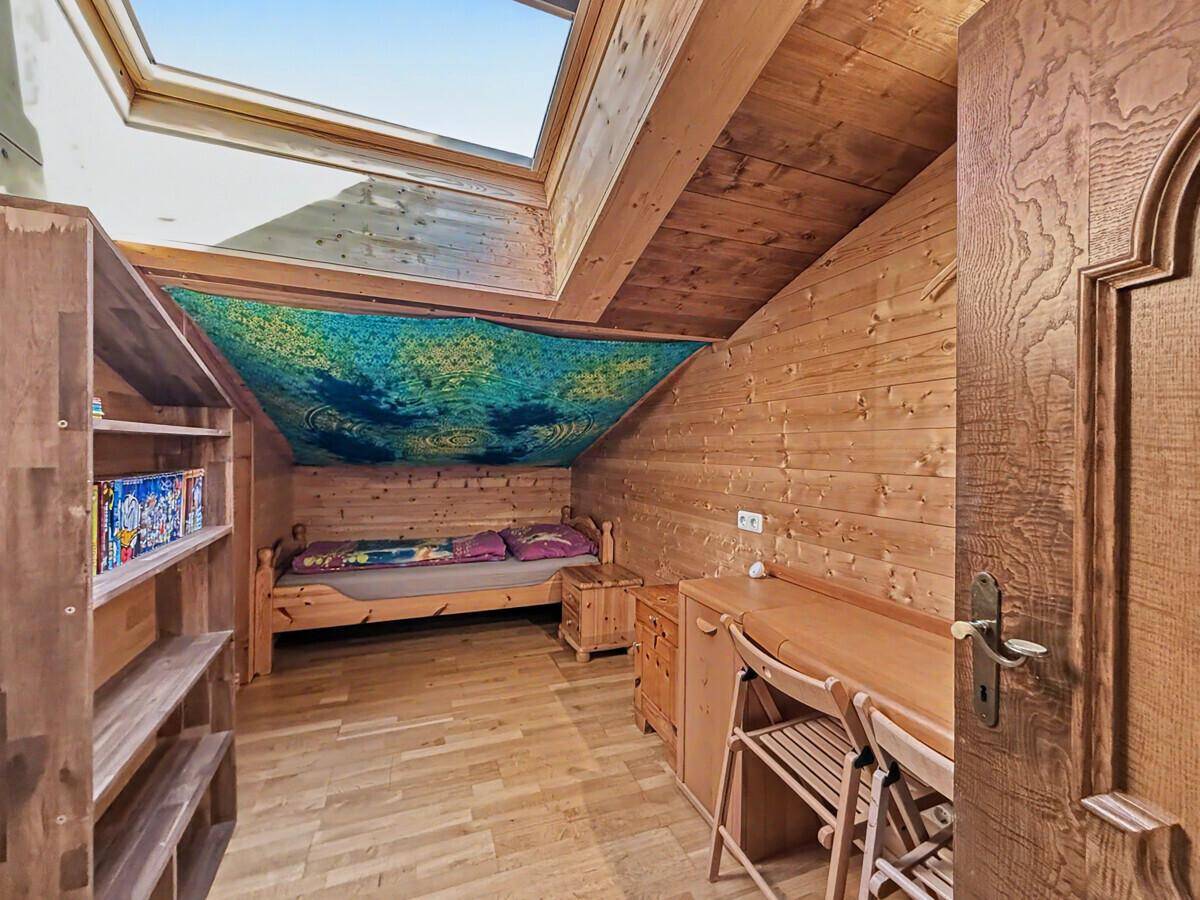 Helles Schlafzimmer mit Einzelbett, Schreibtisch und Dachfenster, ideal als Jugendzimmer.
