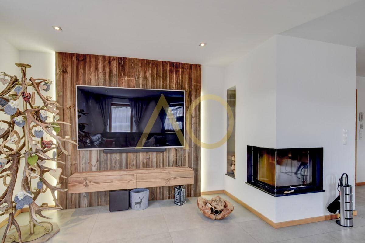 Gemütliches Wohnzimmer mit modernem Kamin, Holzwand und dekorativem Geweih-Element.