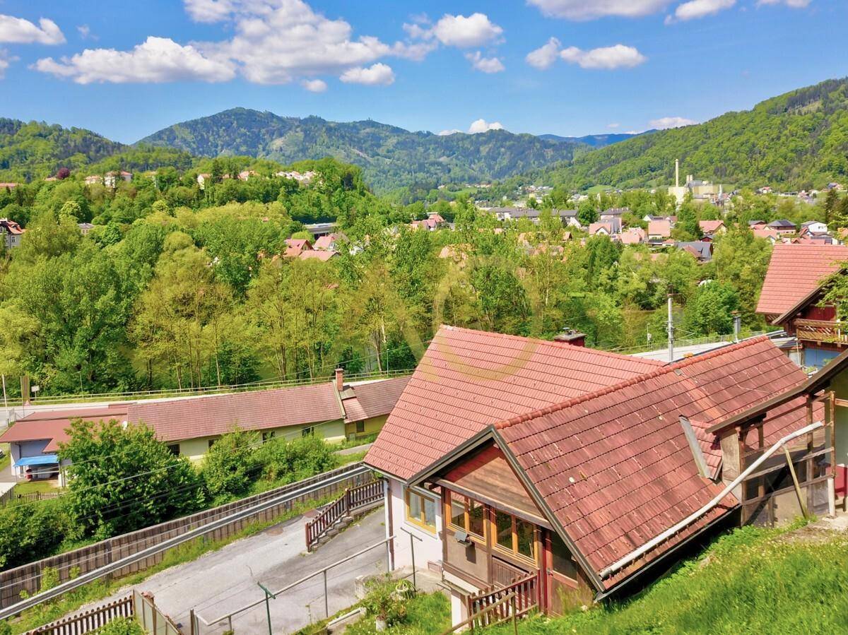 Panoramablick auf das Haus mit rotem Ziegeldach und die umliegende Berglandschaft.