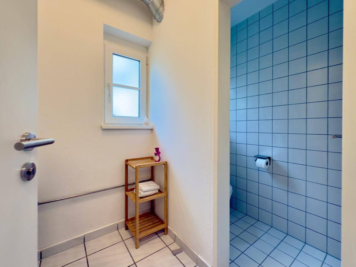 Kleines WC mit Fenster, Fliesenboden und einfacher Ausstattung.