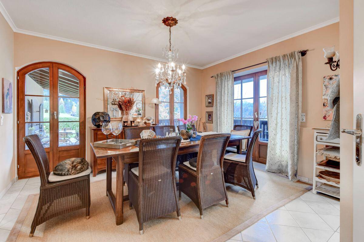 Eleganter Essbereich mit Kronleuchter, Korbstühlen und Zugang zur Terrasse.