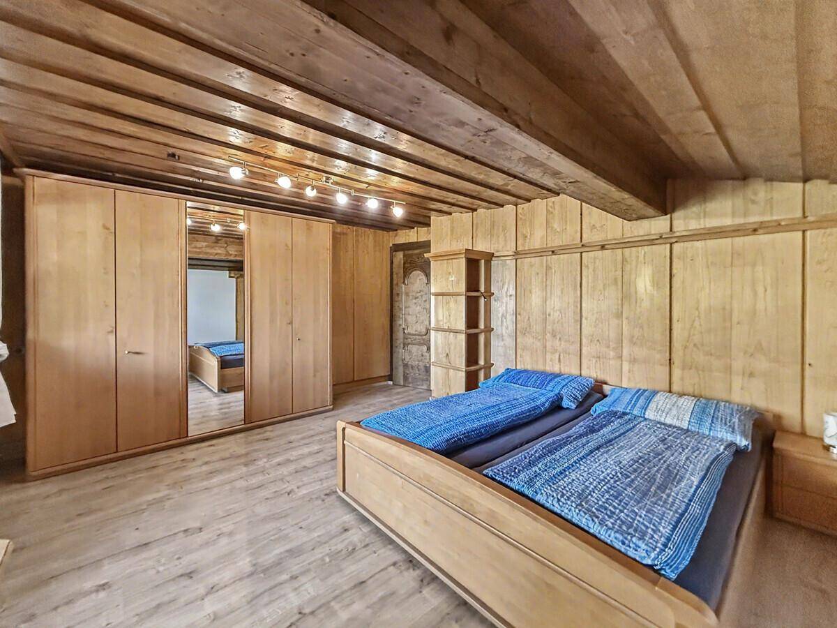 Geräumiges Schlafzimmer mit Holzbett, großem Spiegelschrank und rustikaler Holzverkleidung.