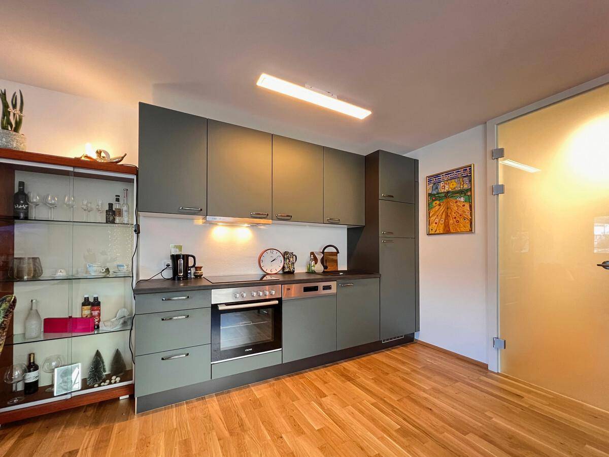 Moderne Einbauküche mit grauen Schränken, integrierten Geräten und Holzboden.