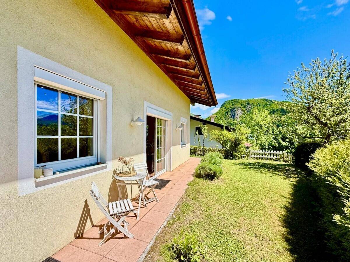 Sonniger Terrassenbereich mit Garten und Blick auf die umliegende Berglandschaft.