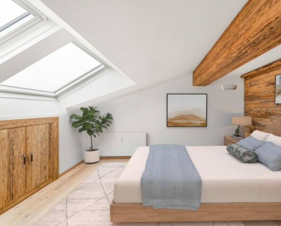 Helles Schlafzimmer im Dachgeschoss mit großen Dachfenstern, Holzbalken und rustikalen Holzmöbeln.