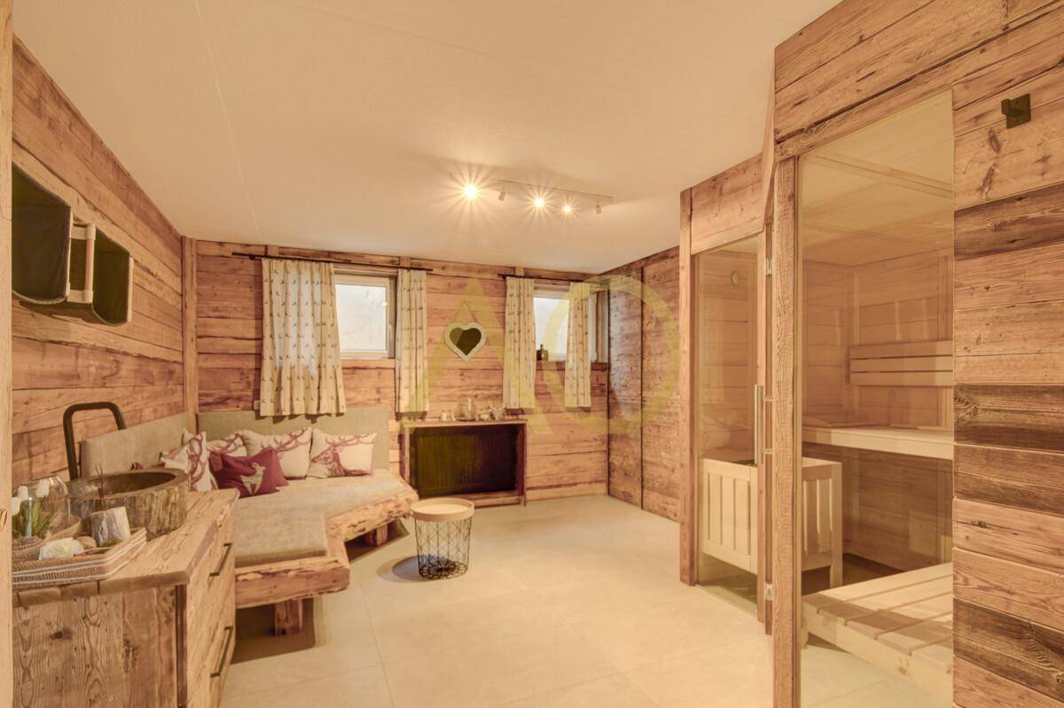 Exklusiver Wellnessbereich mit Sauna, Holzwänden und rustikalem Waschbecken.
