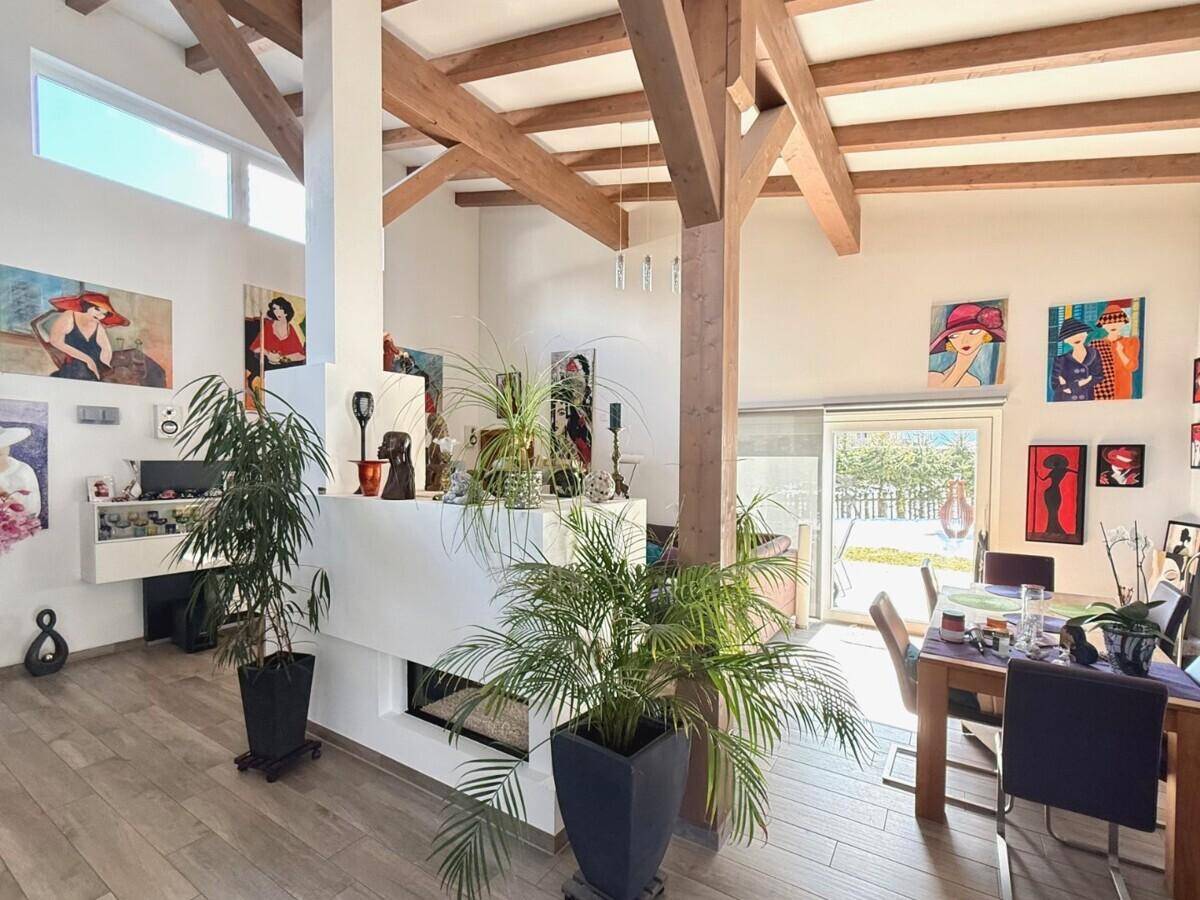 Geräumiger Wohn-Essbereich mit hohen Decken, Holzbalken und einem modernen Kamin.
