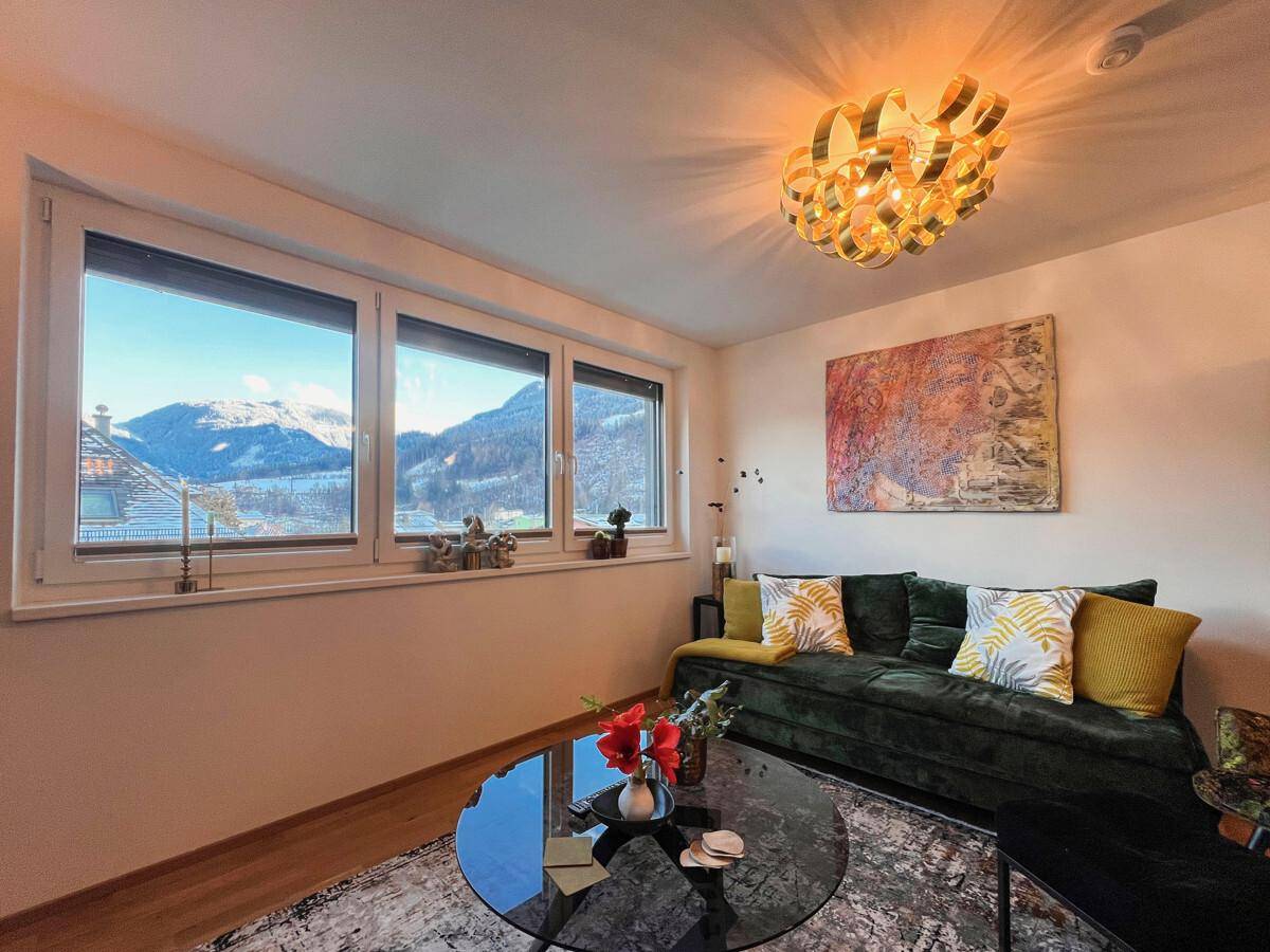 Gemütliches Wohnzimmer mit Blick auf schneebedeckte Berge und stilvoller Beleuchtung.