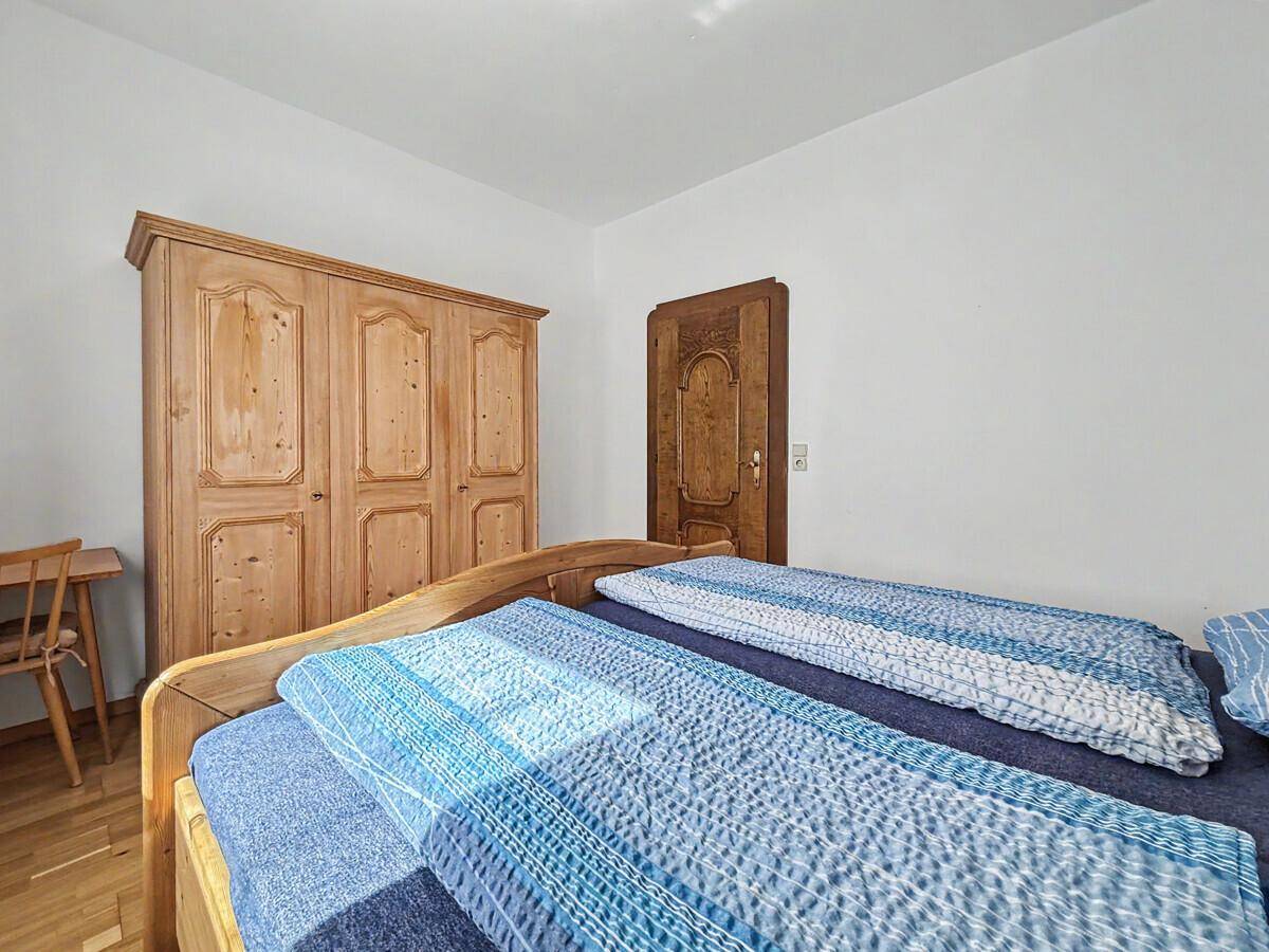 Gemütliches Schlafzimmer mit traditionellen Holzmöbeln und hellem Parkettboden.