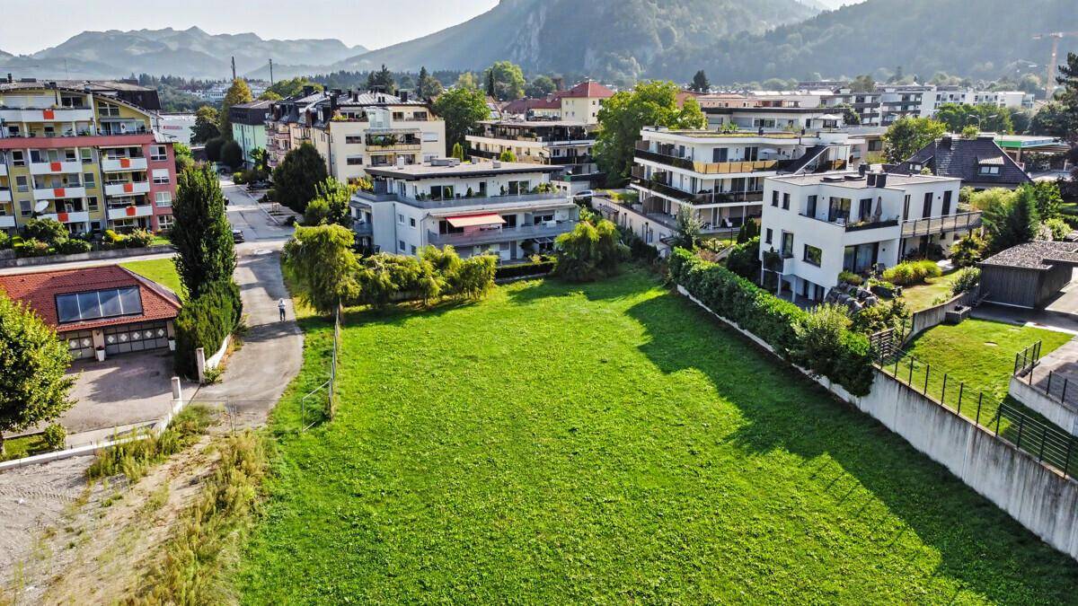 Luftaufnahme einer weitläufigen Grünfläche, umgeben von modernen Wohngebäuden und Straßen.
