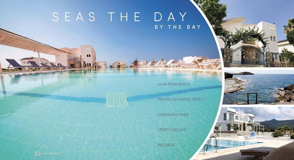 Große Resort-Poolanlage mit Sonnenliegen und Meerblick, umgeben von modernen Gebäuden und Küstenlandschaft.