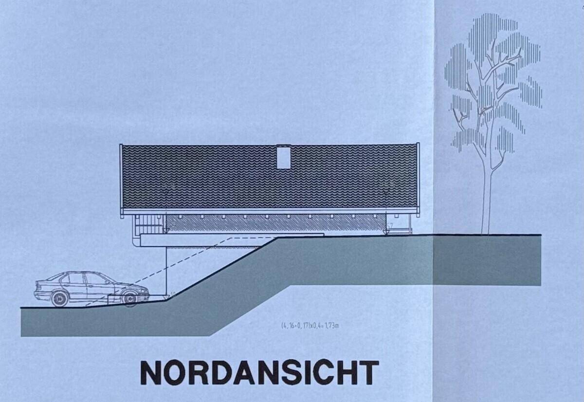 Nordansicht des Gebäudes mit flacherer Dachlinie und Zufahrt für ein Fahrzeug.