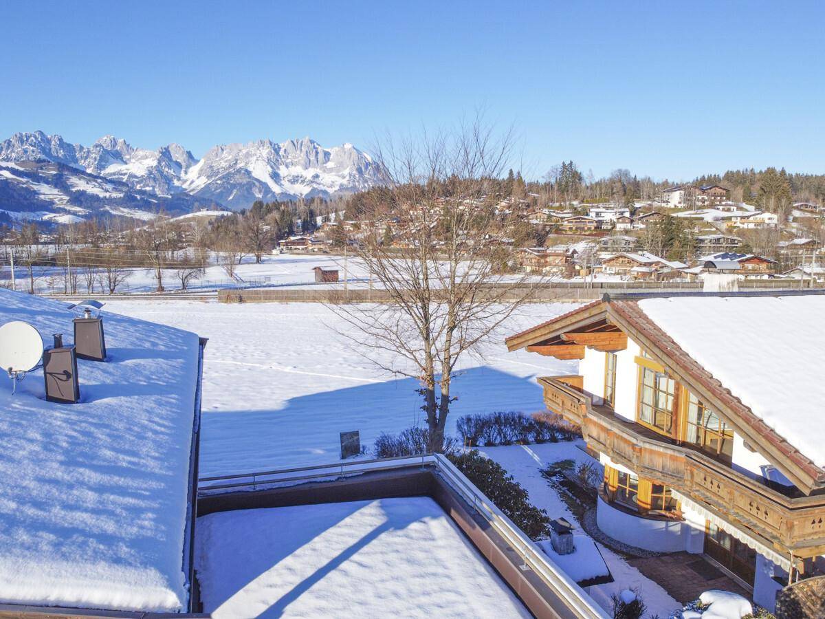 Weitläufige Winterlandschaft mit schneebedeckten Feldern und einer imposanten Bergkulisse.