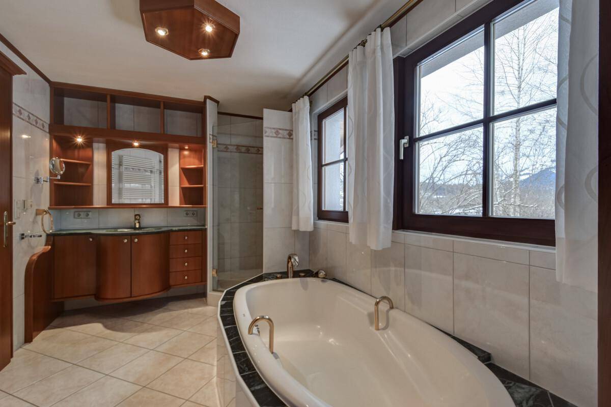 Geräumiges Badezimmer mit Badewanne, Dusche, Doppelwaschbecken und Fenster mit Ausblick.