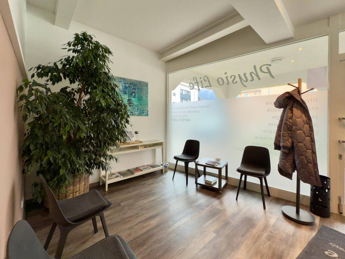 Gemütlicher Wartebereich mit Sitzgelegenheiten, Garderobe und Blick nach draußen.