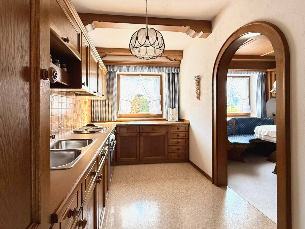 Traditionelle Küche mit Holzschränken, gefliestem Spritzschutz und Blick ins Esszimmer.