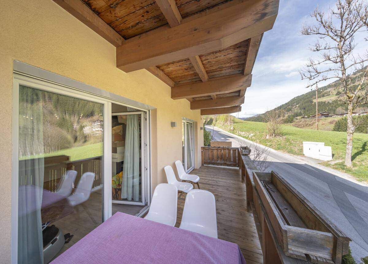 Geräumiger Balkon mit Sitzgelegenheiten und Blick auf die umliegende Berglandschaft und Straße.