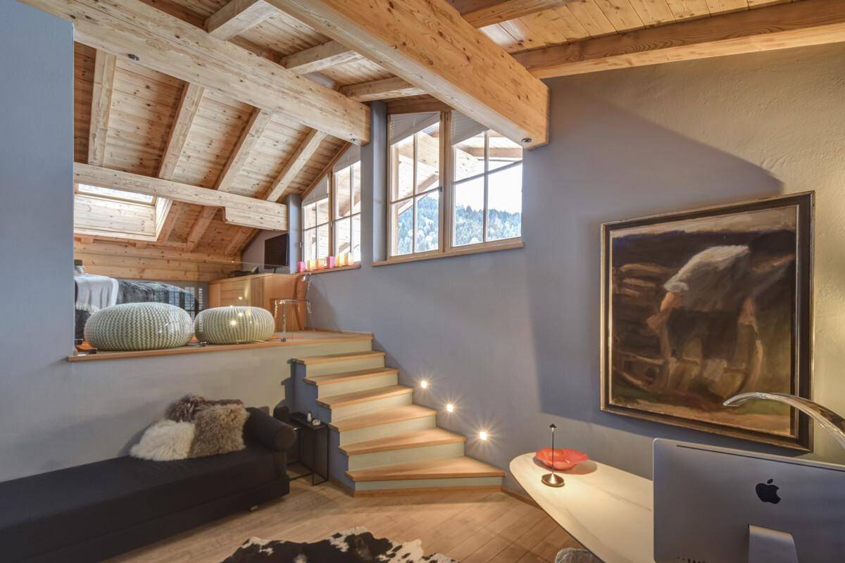 Gemütlicher Loft-Bereich mit Schreibtisch, Holzbalkendecke und Fenstern mit Bergblick.