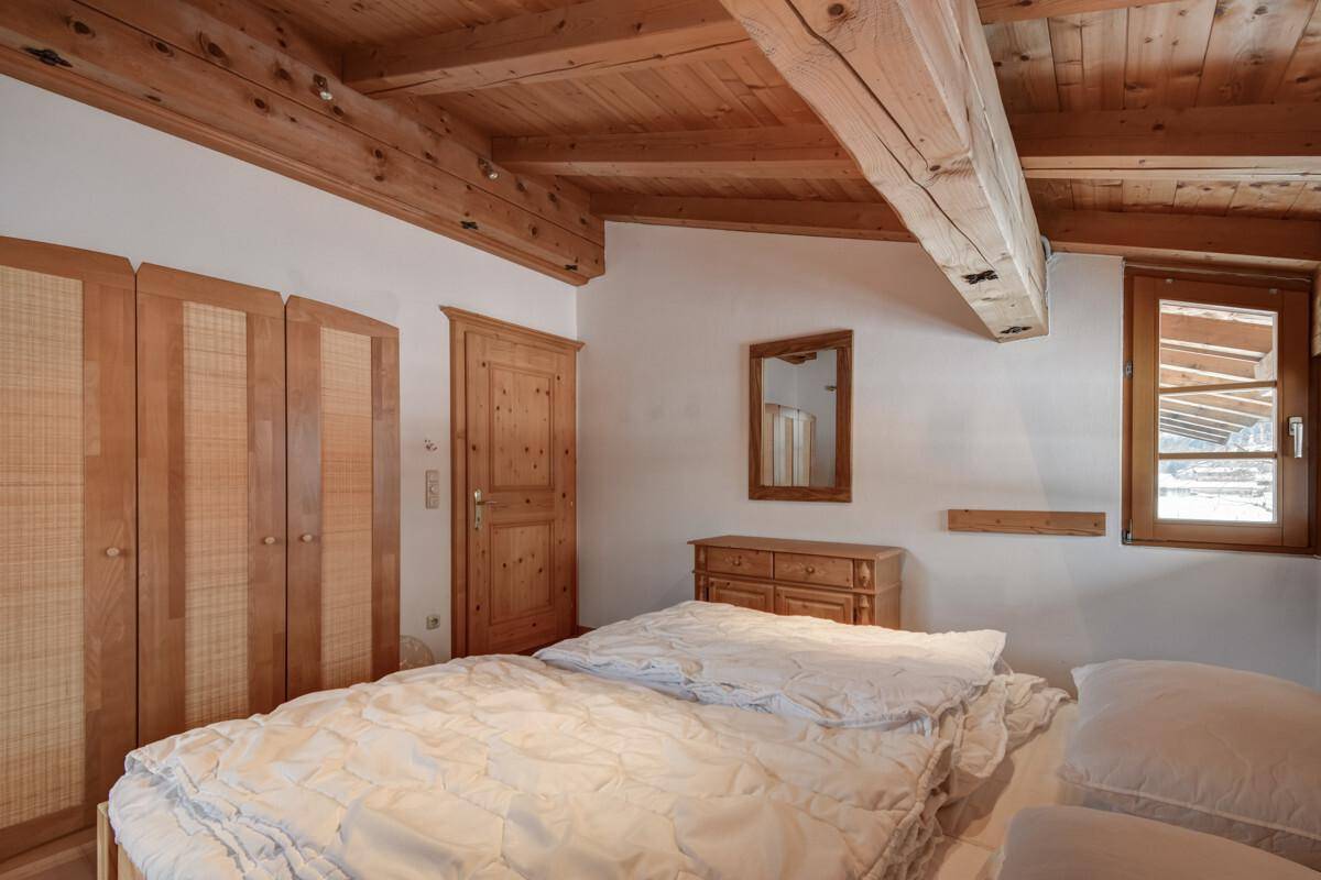Gemütliches Schlafzimmer mit Holzbalkendecke, Parkettboden und traditionellen Holzmöbeln.