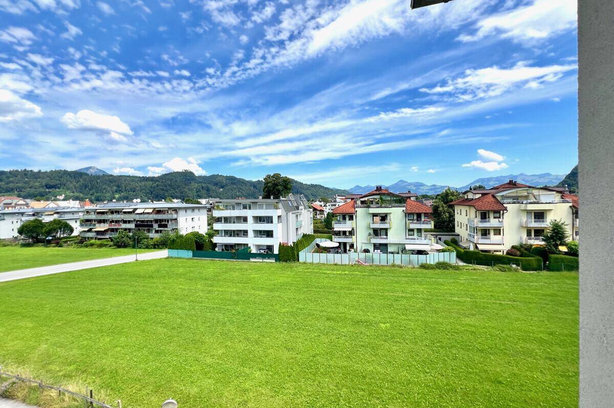 Weitläufiger Blick über grüne Felder und die umliegende Berglandschaft.