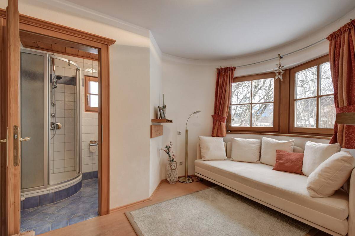 Kleiner Sitzbereich mit Fenster und Blick auf die Berge, angrenzend an ein Duschbad.