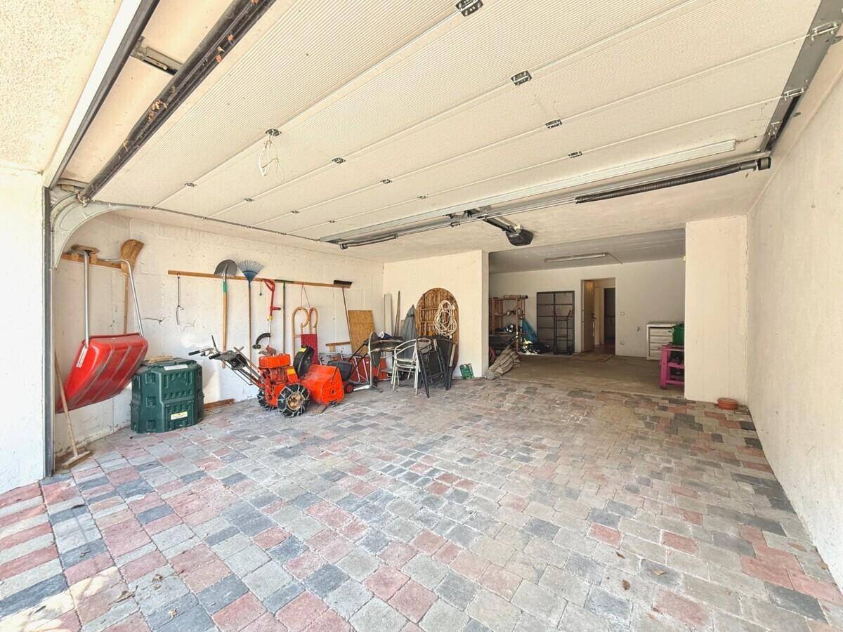 Geräumige Garage mit Pflasterboden und viel Stauraum für Werkzeuge und Geräte.