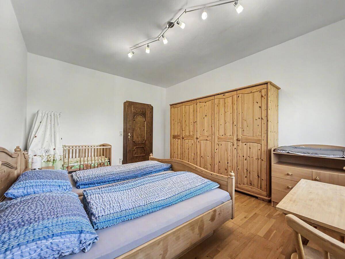 Helles Schlafzimmer mit Holzbett, Kleiderschrank und Babybett, ideal für Familien.