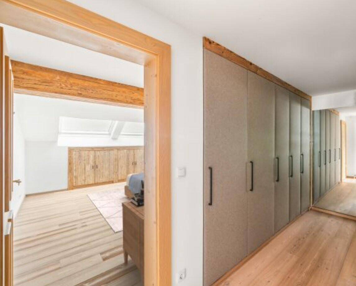 Langer Flur mit integrierten Einbauschränken und Blick in ein helles Schlafzimmer mit Dachfenstern.