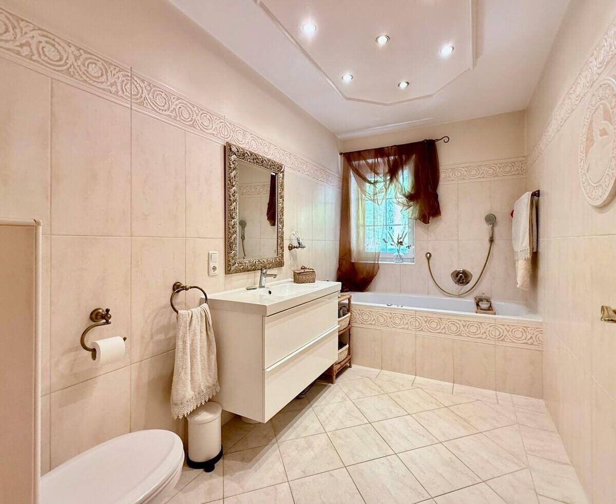 Helles Badezimmer mit Badewanne, modernem Waschtisch und dekorativen Fliesen.