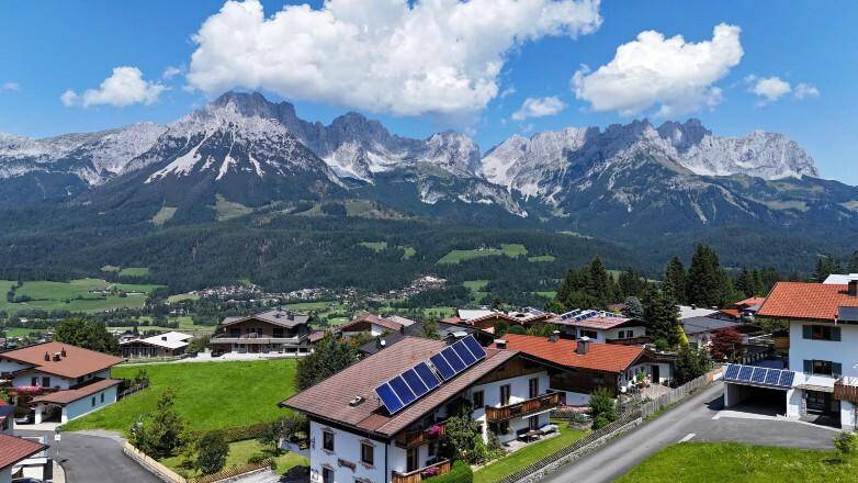 Panoramablick auf ein Bergdorf mit traditionellen Häusern und majestätischer Alpenkulisse.