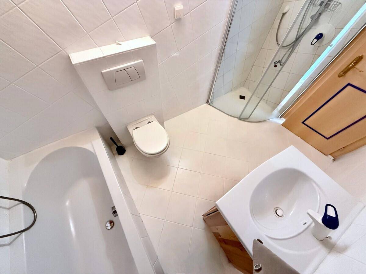 Badezimmer mit Badewanne, Toilette, Waschbecken und Duschkabine, alles in Weiß gehalten.
