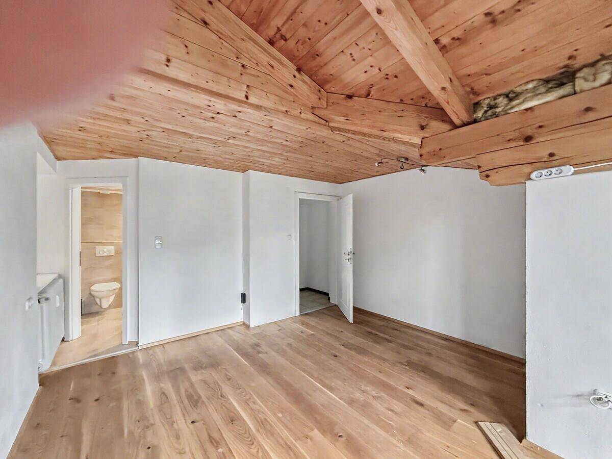 Schlafzimmer mit Holzbalkendecke, Holzboden und Zugang zu einem Badezimmer.