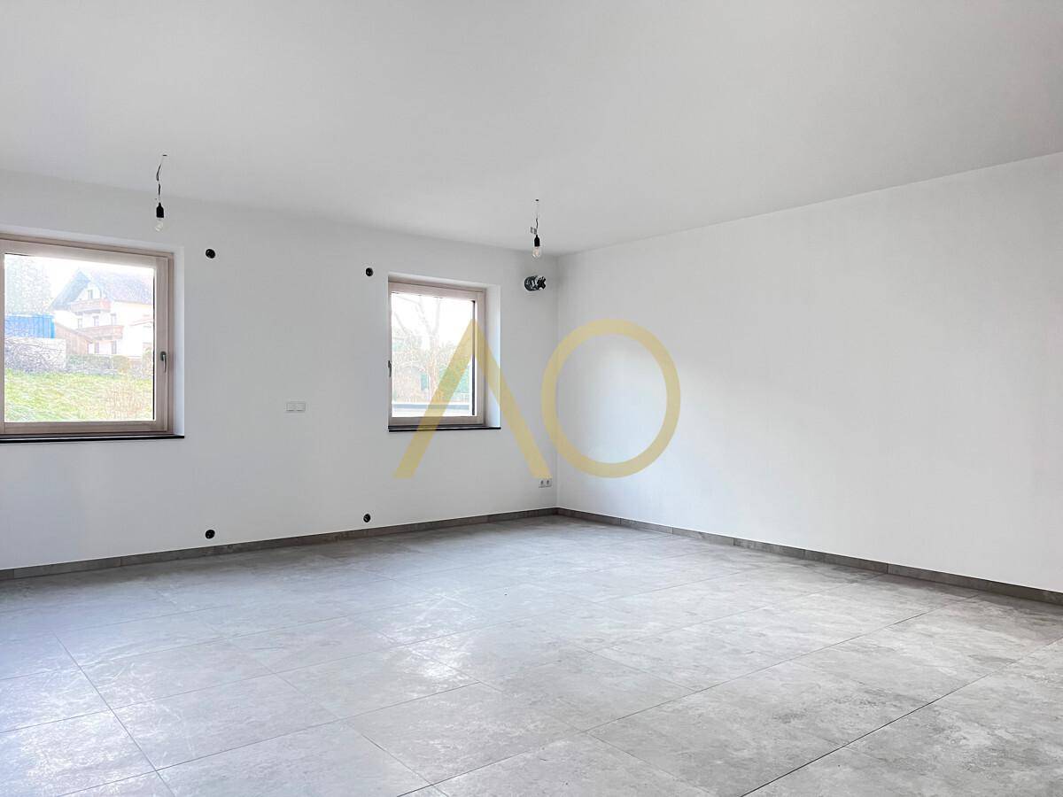 Geräumiges Wohnzimmer mit hellen Fliesen, großen Fenstern und viel Tageslicht.