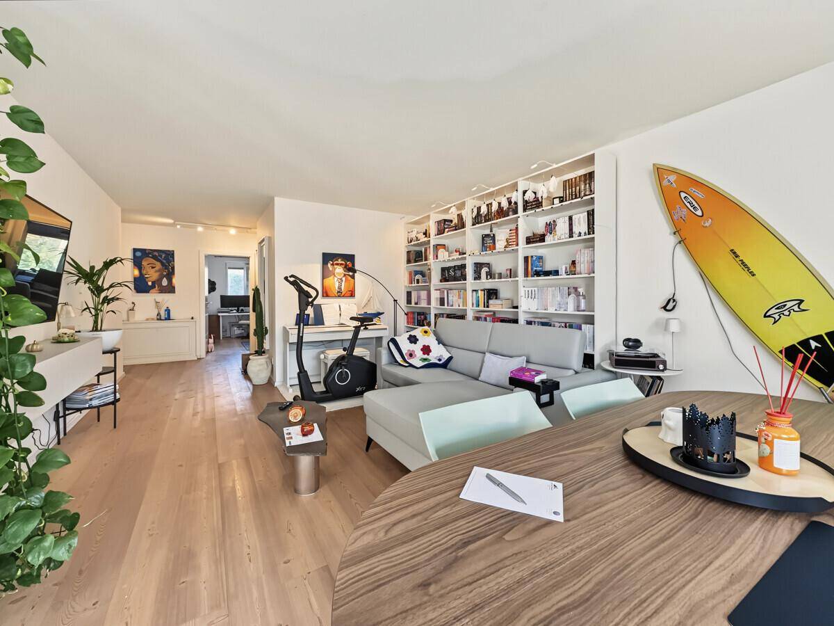 Geräumiges Wohnzimmer mit Holzboden, großer Bücherwand und bequemer Sofalandschaft.