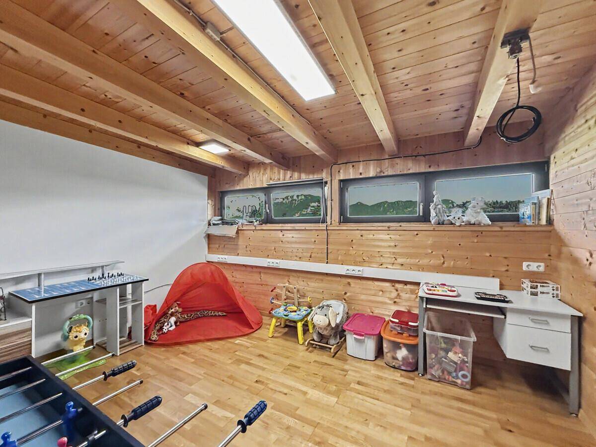 Helles Spielzimmer mit mehreren Fenstern, Holzboden und -wänden, ideal für Kinder.