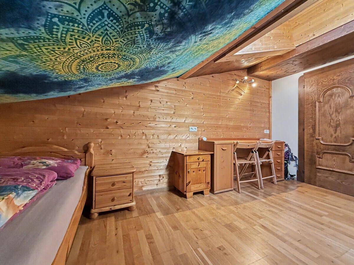 Arbeitsbereich im Schlafzimmer mit Schreibtisch und Holzvertäfelung, unter einem Dachfenster gelegen.