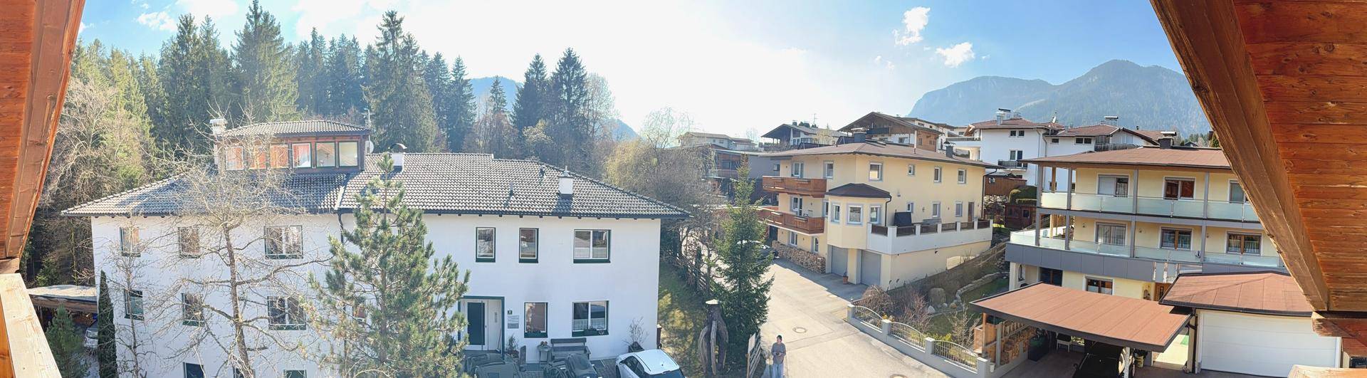 Panoramablick von einem Holzbalcon auf die umliegende Wohnsiedlung und ferne Berge.