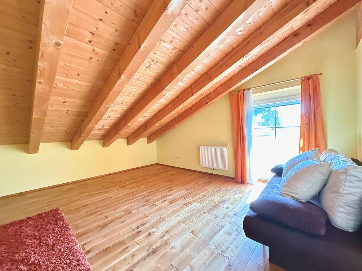Dachgeschosszimmer mit sichtbaren Holzbalken, Holzboden und charakteristischen schrägen Decken.