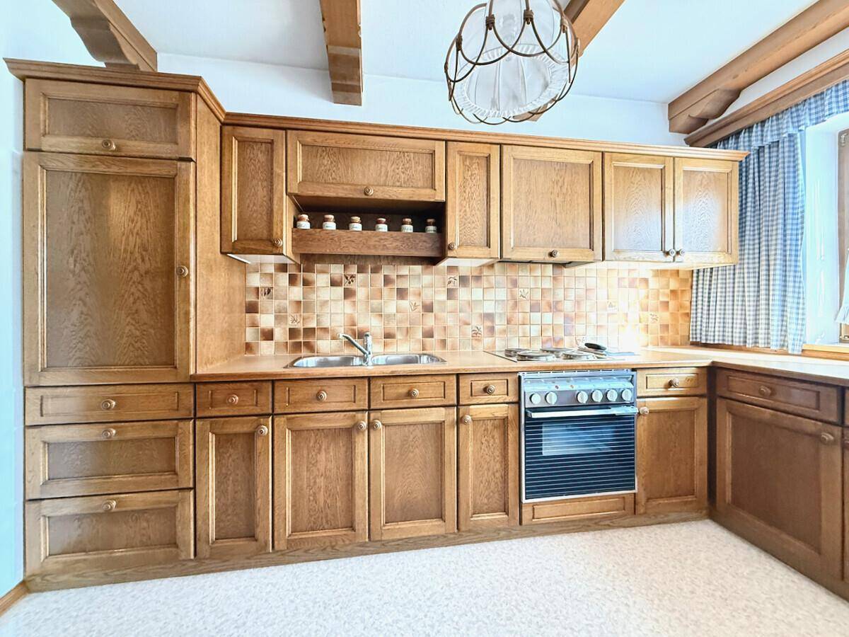 Voll ausgestattete Holzküche im Landhausstil mit Backofen und traditionellen Fliesen.
