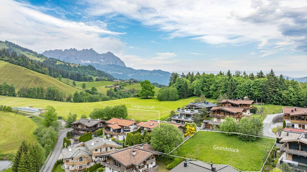 Luftaufnahme einer Wohnsiedlung im alpinen Stil mit Bergblick und grüner Landschaft.