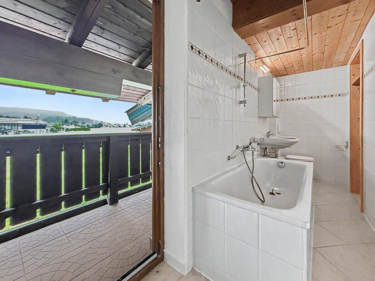 Traditionelles Badezimmer mit Badewanne, WC und Zugang zu einem Balkon.