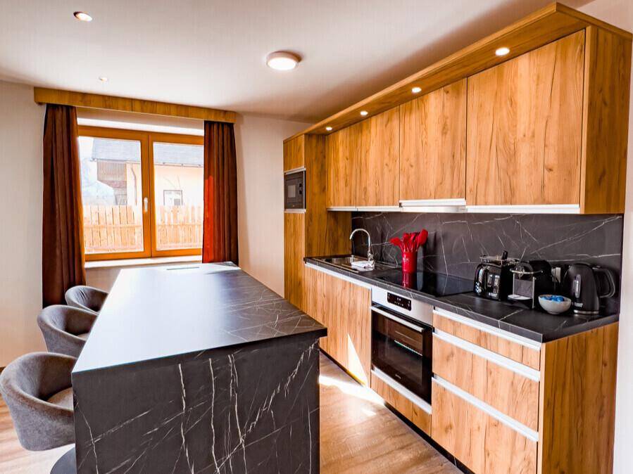 Moderne Küche mit Holzschränken, dunkler Arbeitsplatte und integrierten Geräten.