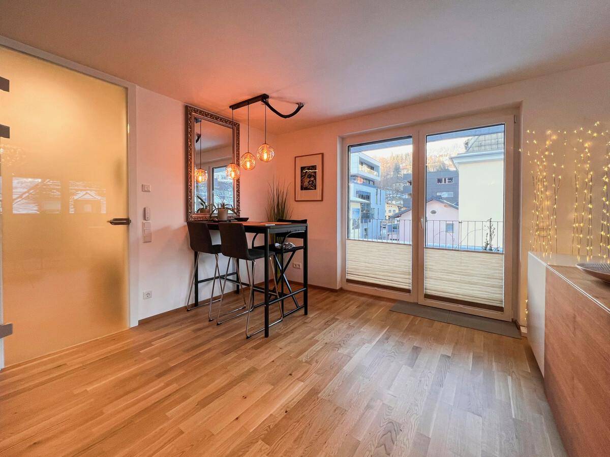 Heller Essbereich mit Bartisch und großem Fenster, das den Zugang zum Balkon ermöglicht.