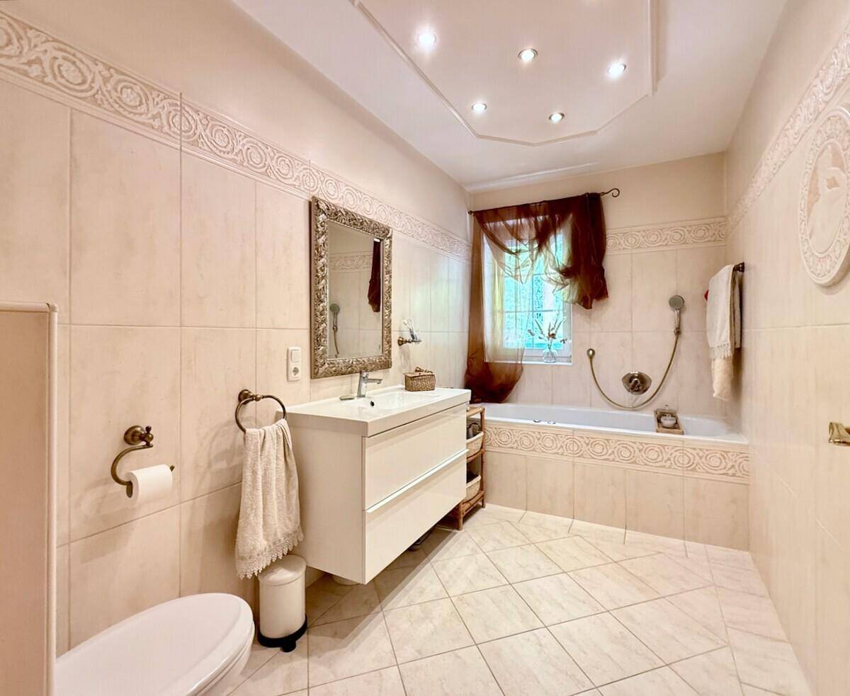 Helles Badezimmer mit Badewanne, modernem Waschtisch und dekorativen Fliesen.