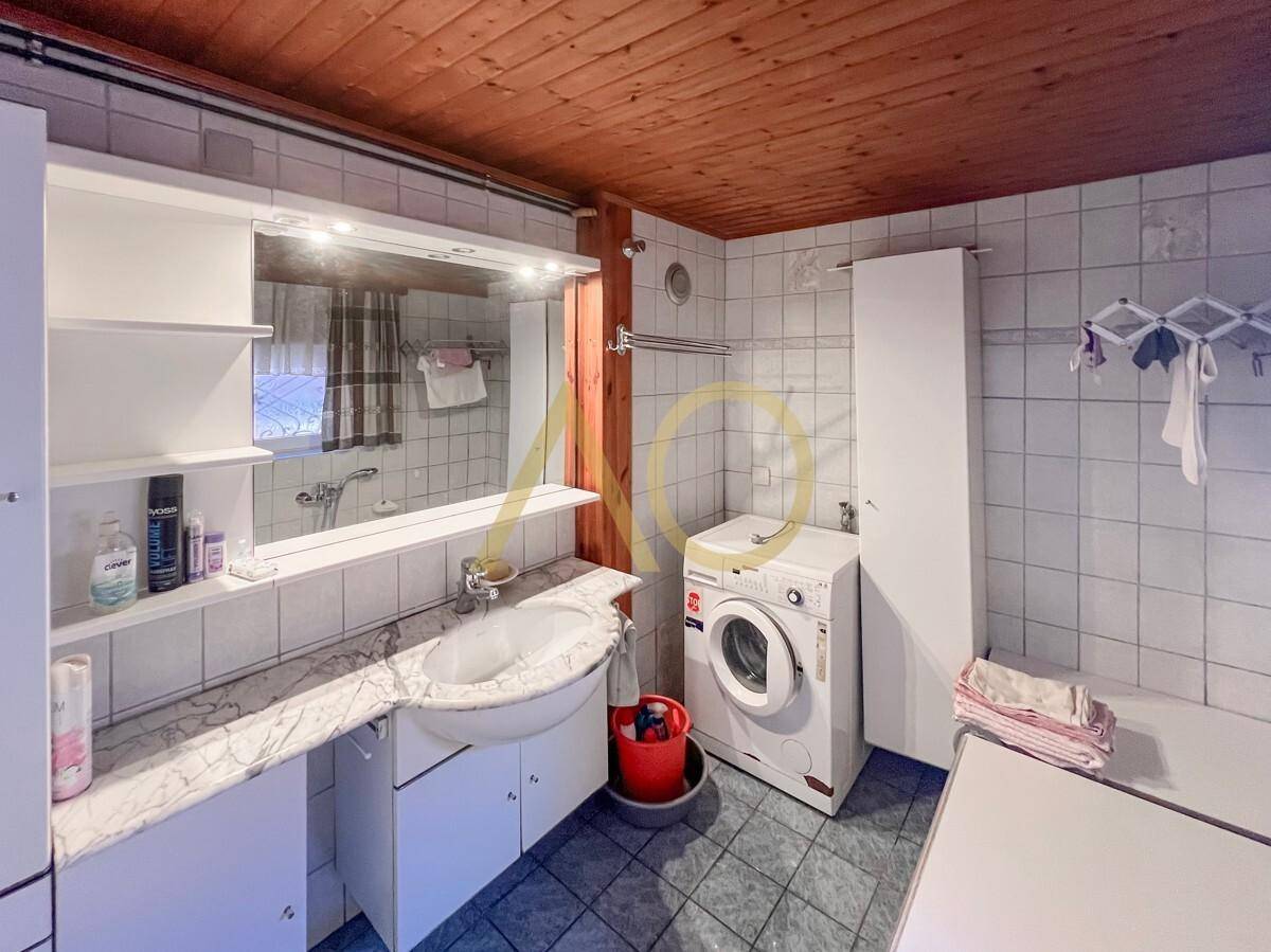 Funktionales Badezimmer mit Fliesen, Holzdecke und integrierter Waschmaschine.