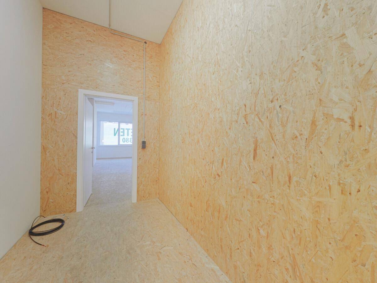 Kleinerer Raum oder Flur mit OSB-Wänden und -Boden, einer Tür und sichtbaren Kabeln, in einem modernen Stil.